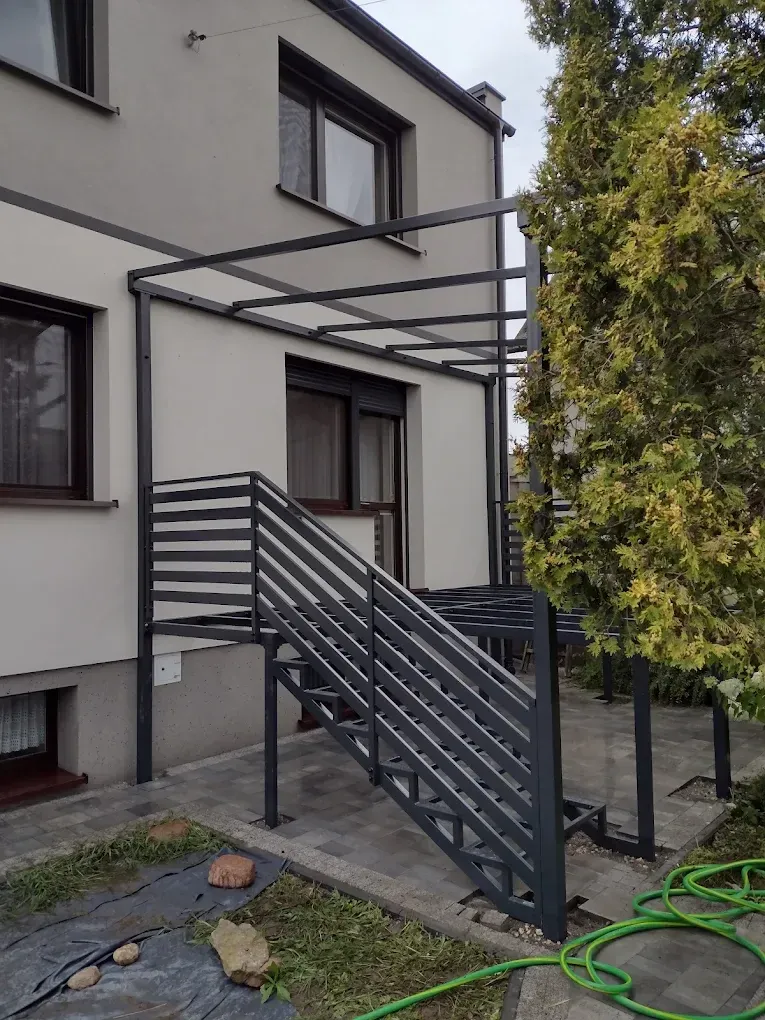 Stalowe schody zewnętrzne z zadaszeniem i poziomą balustradą