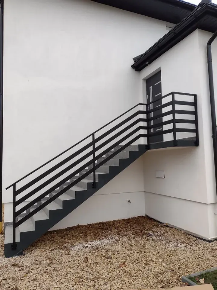Zewnętrzne schody stalowe z poziomą balustradą przy elewacji