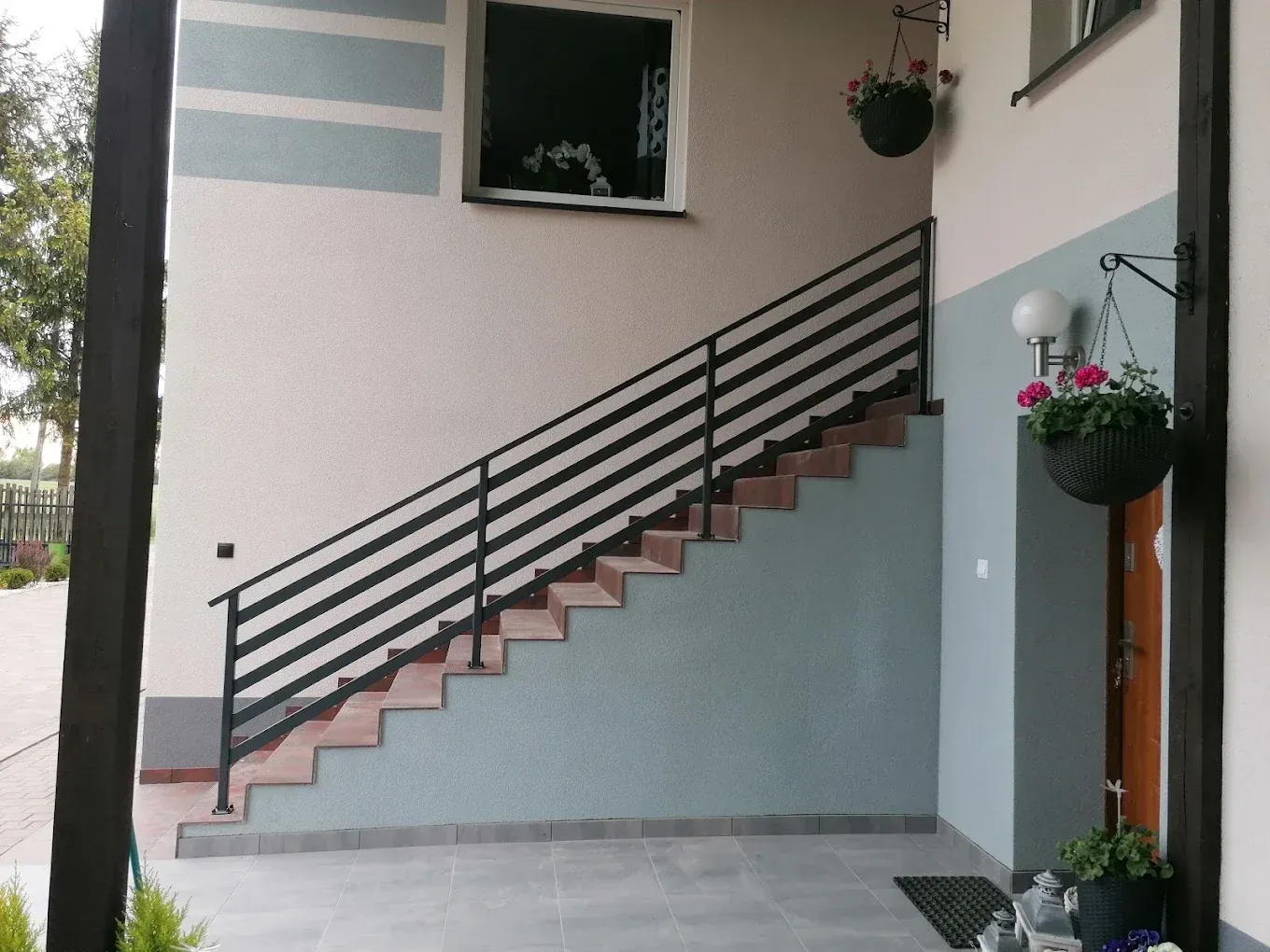 Zewnętrzne schody z poziomą balustradą stalową przy wejściu